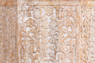Close up image of a hand carved white washed vintage coffee table with floral motif.