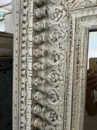 Close up image of a tall white washed wall mirror with hand carved wooden mango wood frame; 180 × 90 × 10 cm.