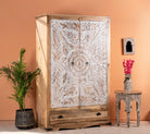 side angle image of a Cheyyur handcrafted solid mango wood wardrobe with hand-carved whitewashed doors, large storage drawer, traditional Indian detailing, and natural wood grain, 190cm.