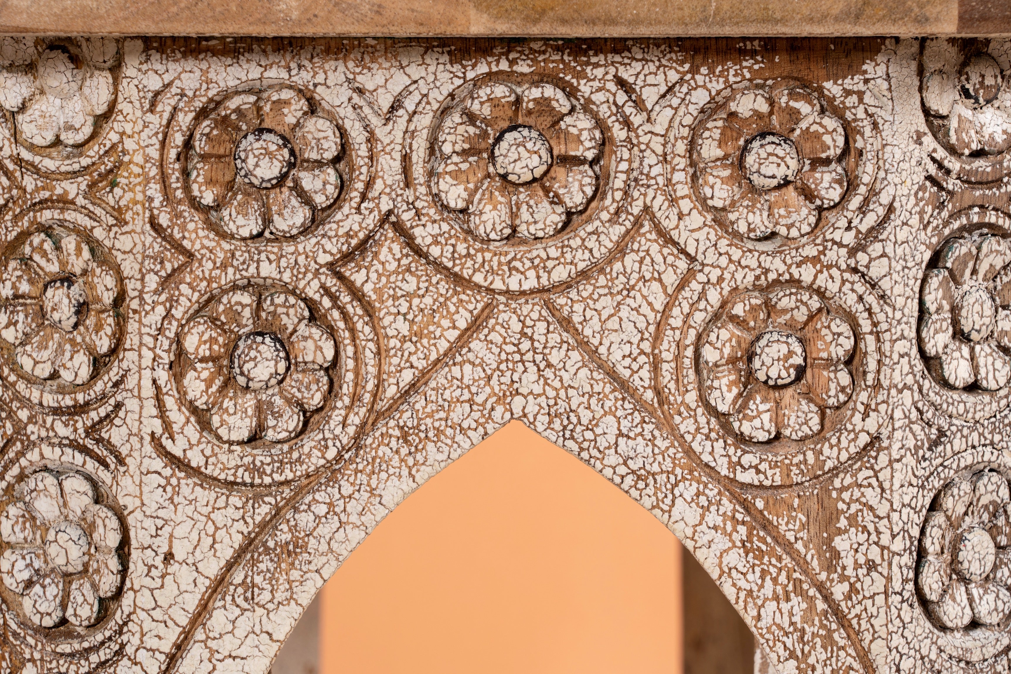 Close up image of a hand carved mango wood coffee table with floral pattern, striking layered colour and vintage charm. A unique wooden accent for your home.