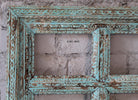 Close up image of a tall carved mango wood mirror Khidakee with floral detailing and vintage window frame inspiration. A unique wooden wall decoration and artisanal furniture piece ideal for vintage and boho interiors.