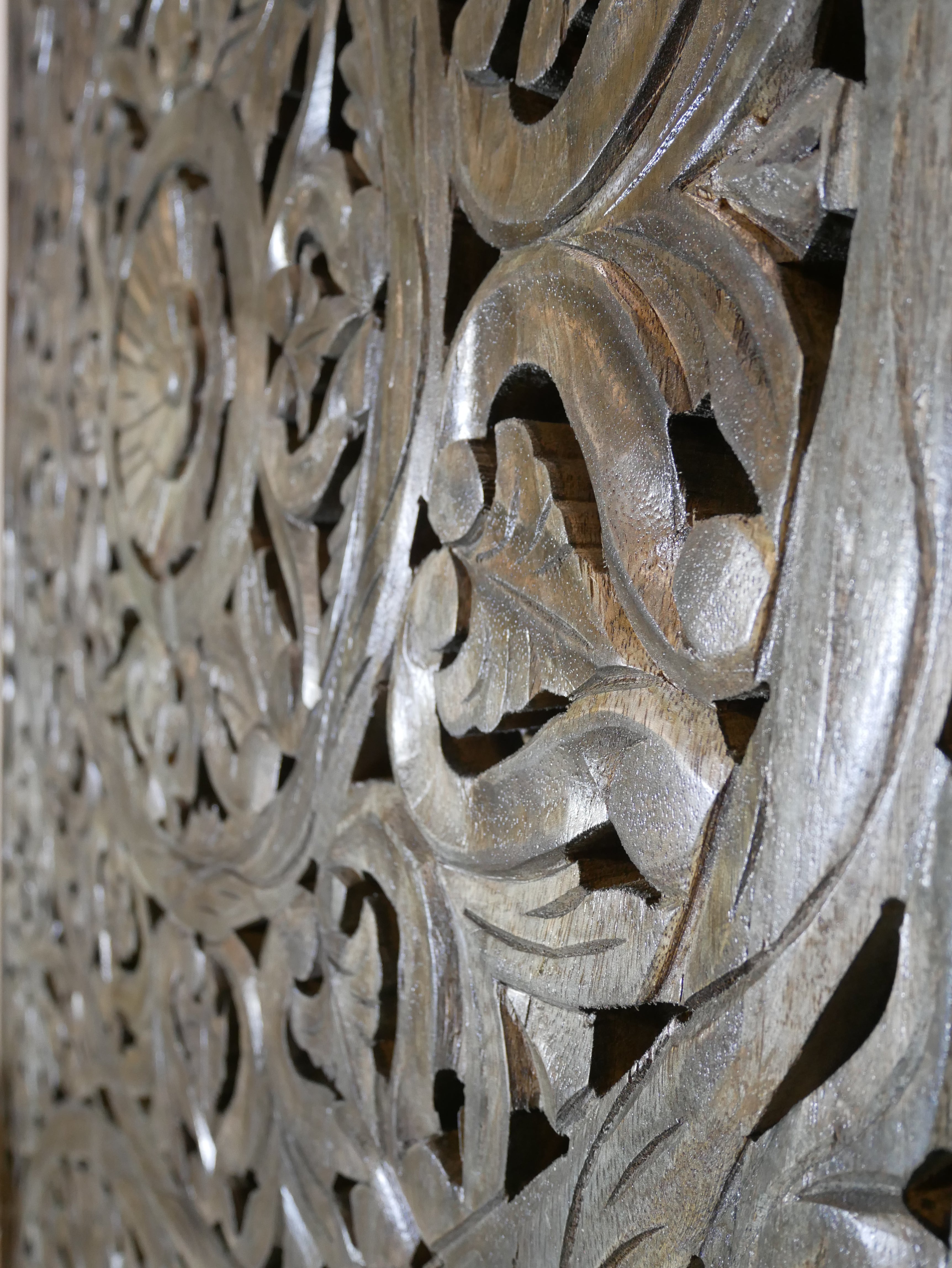Close up image of a hand-carved solid mango wood wall panel with floral designs and a striking grey-green finish, ideal as unique wall décor or a bed panel.