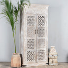 Side angle image of a Hand-carved mango wood wardrobe with whitewashed finish, bedroom furniture wooden wardrobe with floral and geometric lattice doors, 90 × 190 × 40 cm.