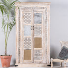 Whitewashed mango wood cabinet with hand-carved details, rattan inserts, and glass panels; versatile as bedroom furniture or wooden wardrobe; 192 × 110 × 40 cm.