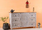 Side angle image of a handcrafted mango wood sideboard with carved floral motifs, whitewashed base and natural top; perfect for vintage home decor and living room furniture, 150 × 40 × 90 cm.
