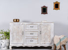 Lifestyle image of a mediterranean-style carved sideboard in solid mango wood with floral motifs and elegant legs; ideal for vintage home decor, 150 × 90 × 40 cm.